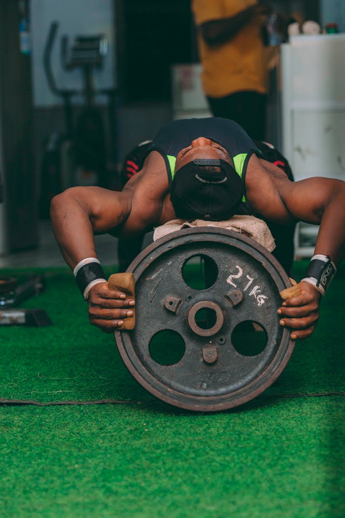 A fit African male athlete lifting a 27kg weight in a gym, demonstrating strength and fitness.