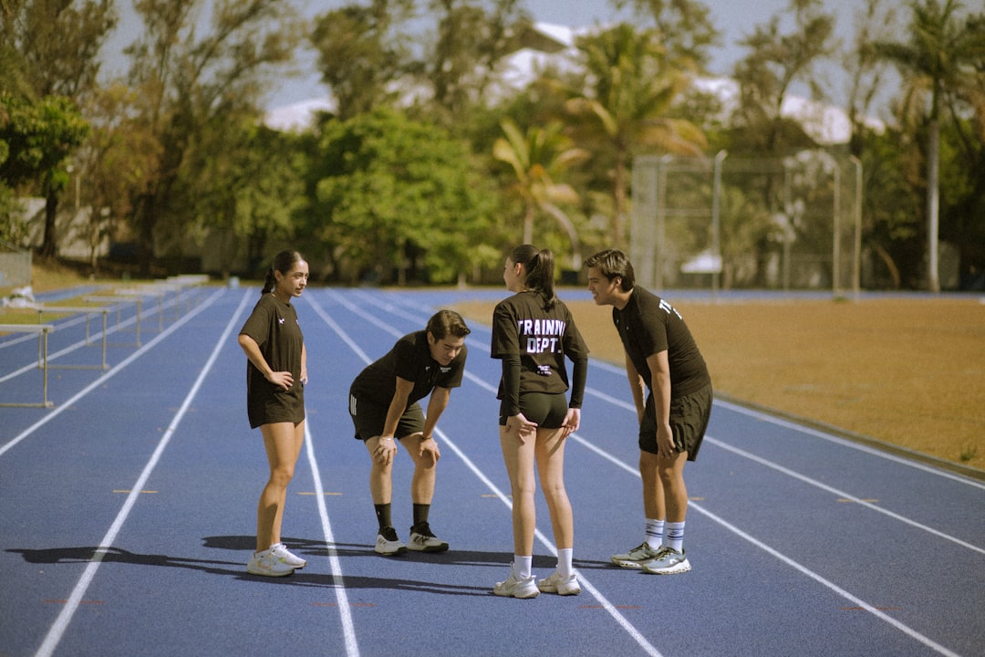 four-athletes-in-black-on-a-blue-running-track-clrutvjkbk8